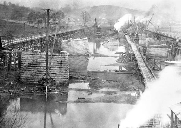 Historic photo of destroyed bridge piers and new temporary spans over the Great Miami River after the 1913 flood